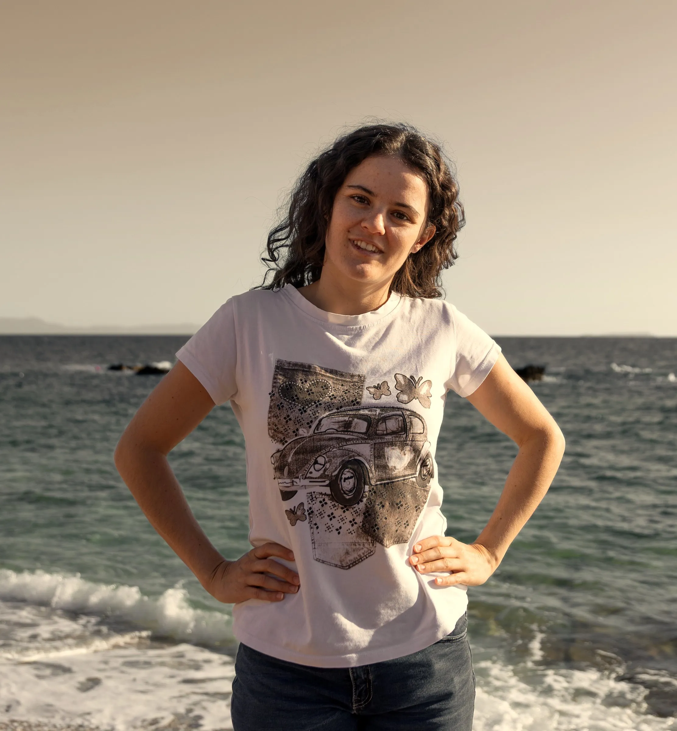 Grace steht am Strand, die Hände in den Hüften